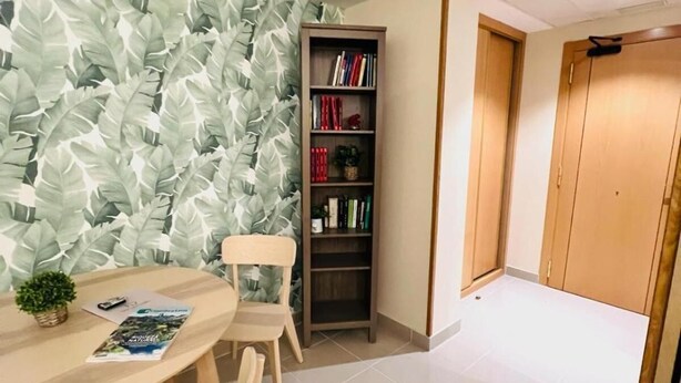 Een moderne kamer met een ronde tafel, twee stoelen, een boekenkast en een behang met een patroon.