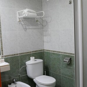 Un baño con inodoro, bidé y toallero.