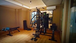 Uma academia com equipamentos de ginástica, um banco e um saco de pancadas.