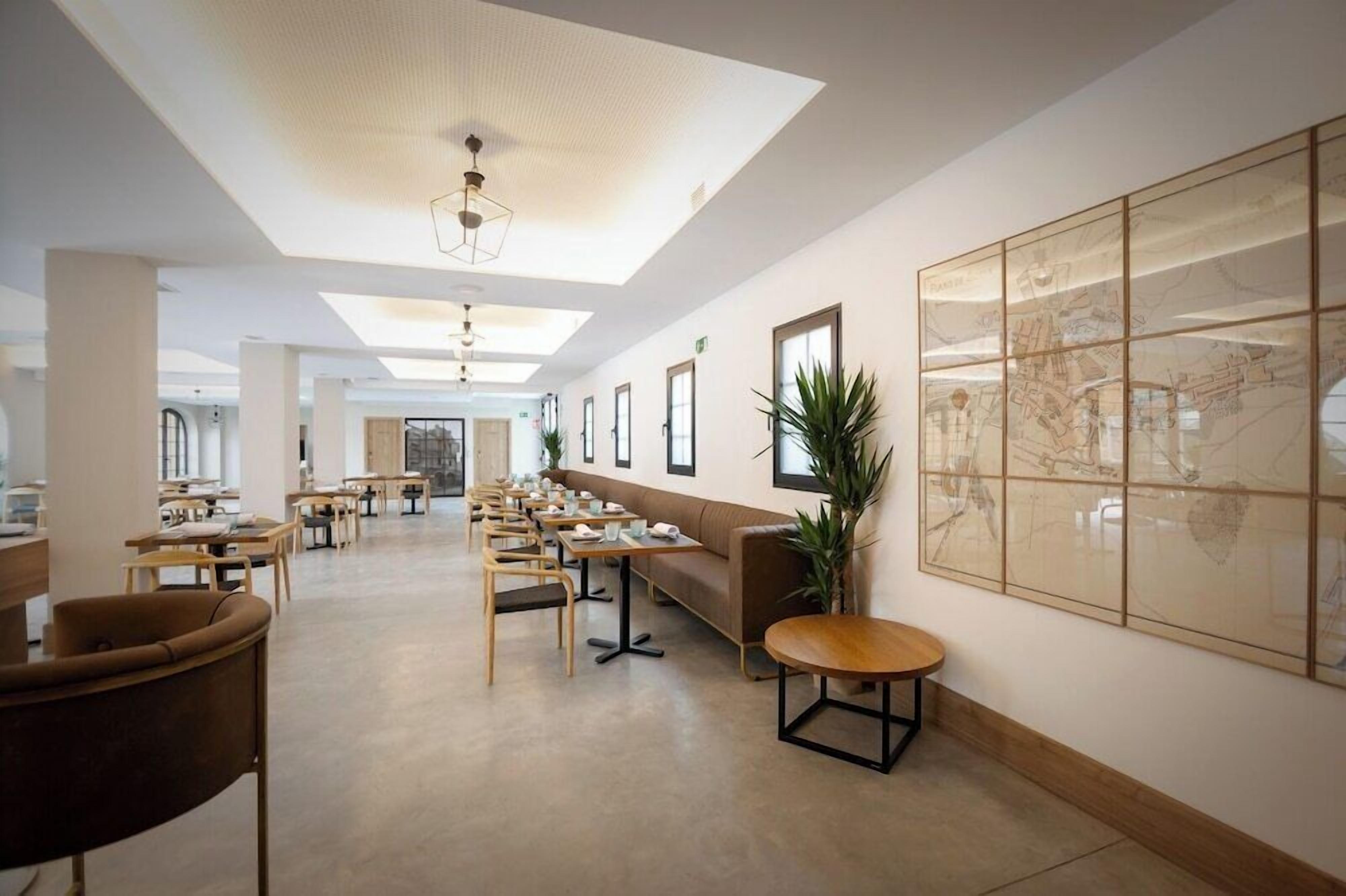 A spacious, modern dining area with long tables, comfortable seating, and a large wall-mounted map.