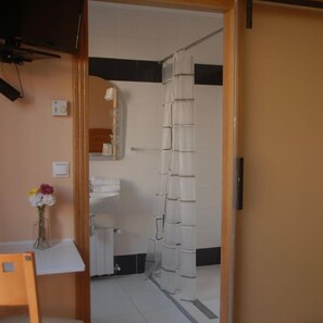 Une salle de bain avec un rideau de douche, un miroir, un lavabo et un vase de fleurs.