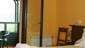 A room with a bed, a chair, a radiator, and a window. - Hotel Restaurante Canero (Valdes)