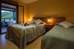 Ett hotellrum med två sängar, en balkong med ett bord och stolar samt utsikt över omgivningarna.