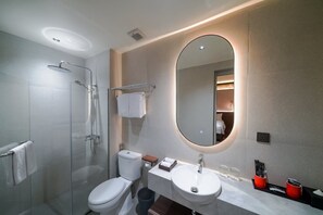 A modern bathroom with a glass-enclosed shower, a toilet, a sink, and a mirror. - Hotel Neo Plus Airport Jakarta (Tangerang)
