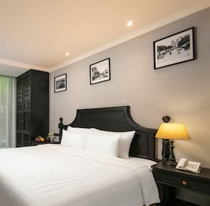 A hotel room with a large bed, a nightstand with a lamp, and three framed pictures on the wall. - Hanoi Paradise Center Hotel & Spa (Hanoi)