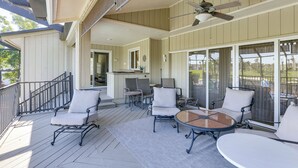 A covered outdoor patio with a ceiling fan, multiple chairs, a table, and a sliding glass door leading to a backyard. - Pool, Spa & Lanai: Upscale Retreat in Fort Myers! (Fort Myers)