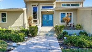A two-story house with a blue front door, a small front porch, and a concrete pathway leading to the entrance. - Pool, Spa & Lanai: Upscale Retreat in Fort Myers! (Fort Myers)