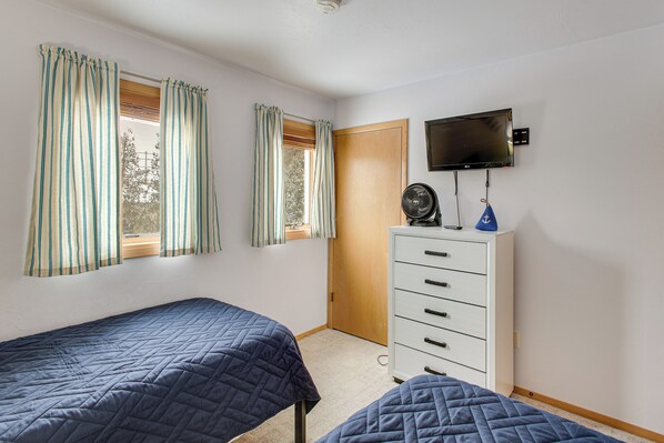 A bedroom with two single beds, a dresser, a television mounted on the wall, and a window with curtains. - Charming DC Getaway Steps from D’town Fish Creek (Fish Creek)