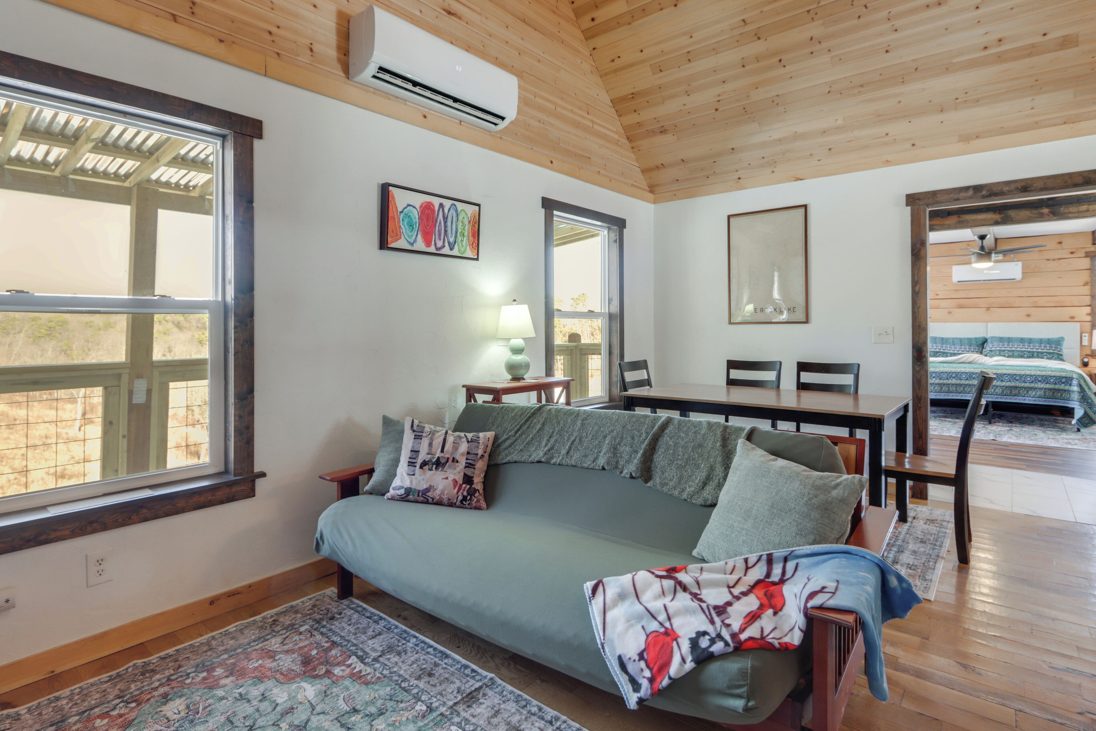A cozy room with a green sofa, a dining table, and a large window.