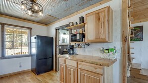 Una cucina con mobili in legno, un frigorifero nero e un piano di lavoro in legno.