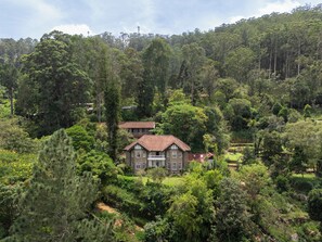 Une grande maison entourée d’une forêt dense.