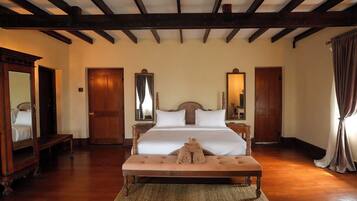 Una habitación de hotel con una cama grande, suelo de madera y techo de madera con vigas a la vista.