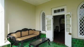 Una habitación con piso de baldosas verdes, un sofá negro con asiento tejido y una mesa a juego.