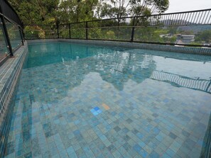 Una piscina con suelo de baldosas y barandilla de metal.