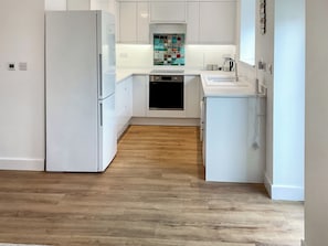 Una cocina moderna con armarios blancos, lavavajillas y salpicadero de azulejos.