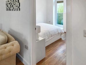 Un dormitorio con cama, mesita de noche, silla y ventana.