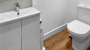 Ein Badezimmer mit Waschbecken, Toilette und Holzboden.