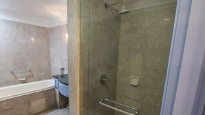 Un baño moderno con ducha envuelta en vidrio, bañera y tocador con espejo.