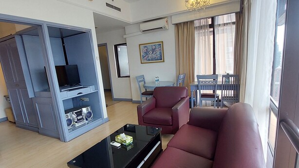 Una sala de estar moderna con un sofá, una mesa de centro y un televisor. Hay una zona de comedor con sillas y una mesa.