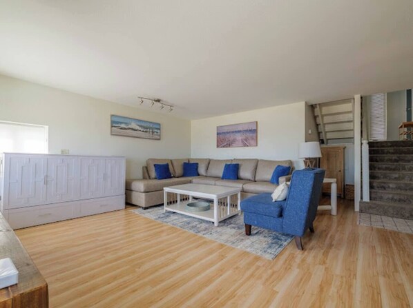 Un salon comprenant un canapé, un fauteuil, une table basse et un meuble.
