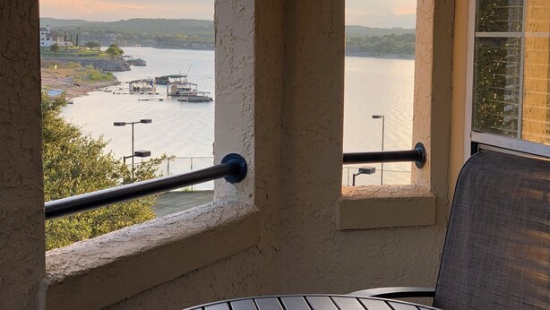 A balcony with a view of a river, a dock, and distant hills. - Relaxing Lago Vista Hill Country Loft w/ Free Parking & Deer Sightings (Lago Vista)