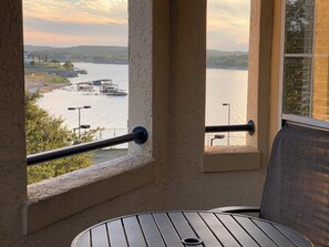 Een balkon met uitzicht op een rivier, een steiger en heuvels in de verte.