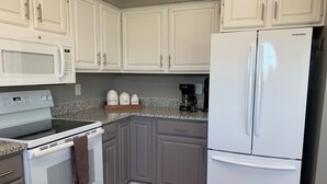 A kitchen with white cabinets, a white refrigerator, a microwave, a stove, and a coffee maker. - Relaxing Lago Vista Hill Country Loft w/ Free Parking & Deer Sightings (Lago Vista)