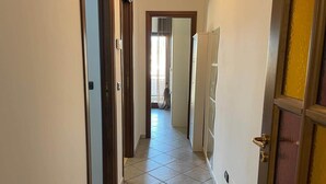 Käytävällä on laatoitettu lattia, ja se johtaa huoneeseen, jossa on ovi.