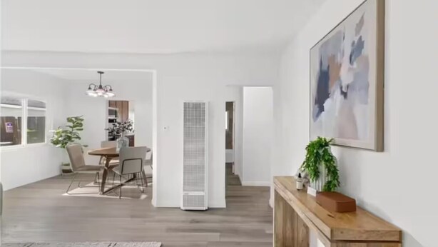 Een ruime woonkamer met een eettafel, stoelen, een potplant en een groot abstract schilderij aan de muur.