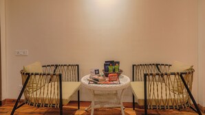 Ein Zimmer mit zwei Korbstühlen, einem kleinen runden Tisch mit Sitzkissen und einigen Gegenständen darauf.