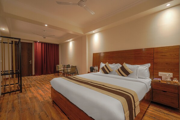 A hotel room with a large bed, wooden headboard, and a nightstand with a lamp. - ELIVAAS Dilli House One room Suits (Kasauli)