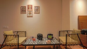 Ein Zimmer mit einem Tisch, zwei Stühlen und drei gerahmten Kunstwerken an der Wand.