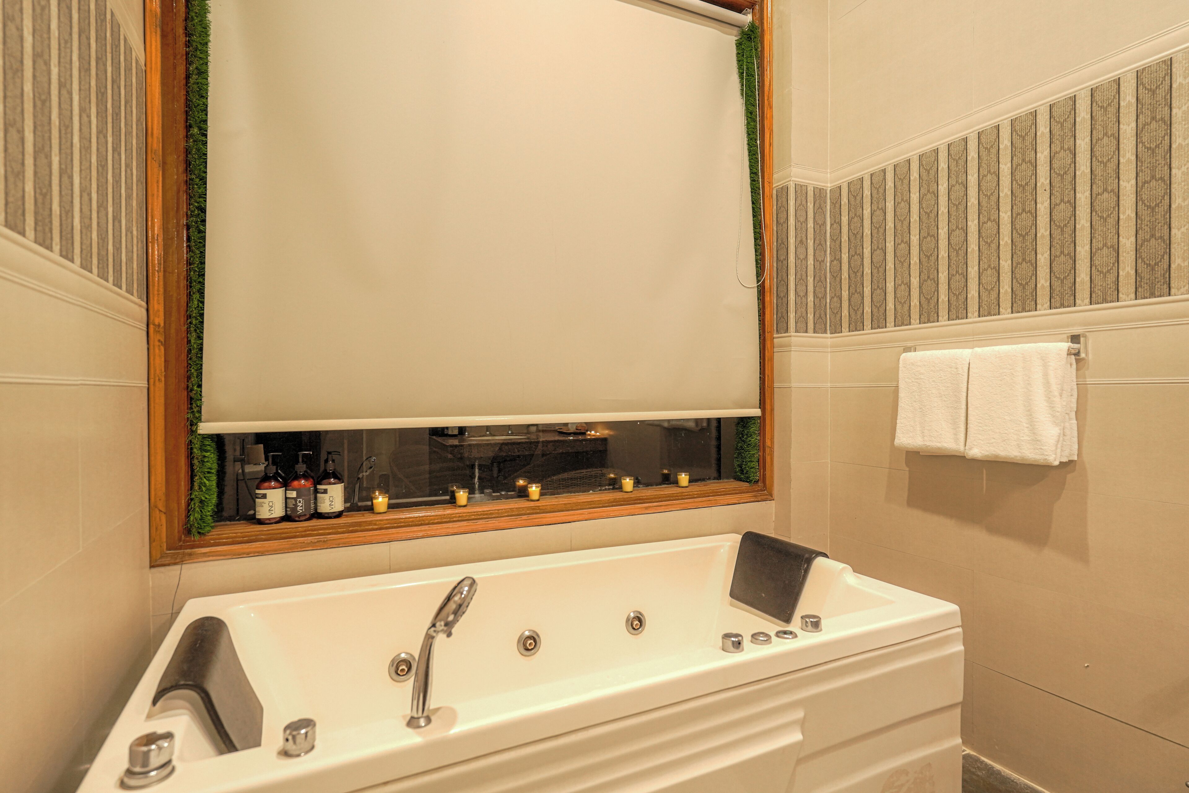 Une salle de bain avec un grand miroir, une baignoire blanche et un porte-serviettes.
