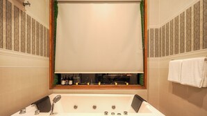 Ein Badezimmer mit einer großen Badewanne, einem Spiegel darüber und einem Handtuchhalter an der Wand.
