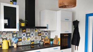 Una cocina moderna con armarios blancos, una campana extractora negra y un salpicadero colorido.