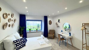 Habitación de hotel con cama, escritorio, silla, ventana y vistas a zonas verdes, además de decoración en las paredes.