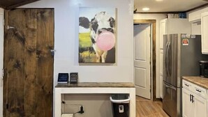 Eine Küche mit Holzbalkendecke, einem Kühlschrank, einem Waschbecken und einem Bild von einer Kuh mit einem rosafarbenen Ballon.