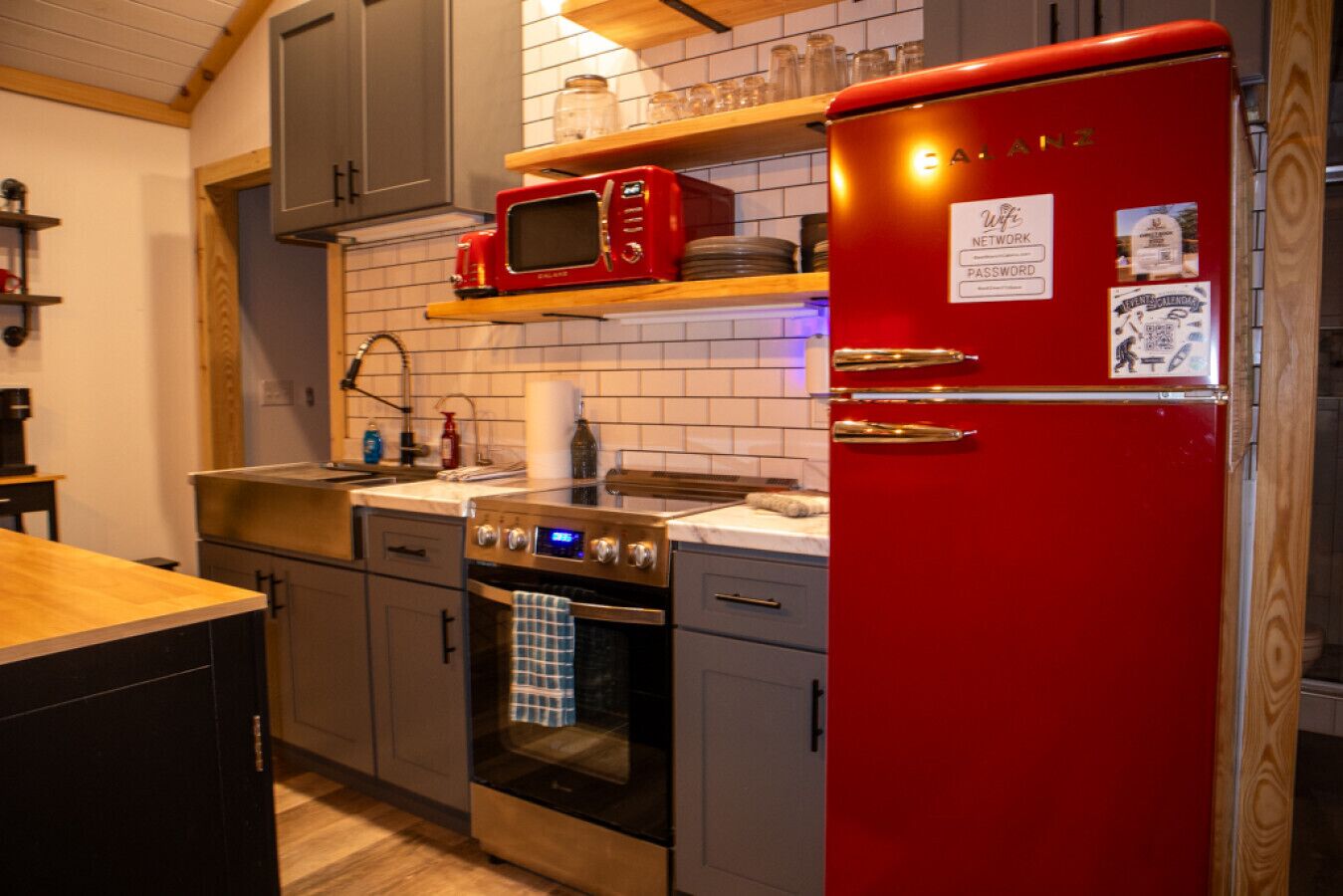 A kitchen with a red refrigerator, a microwave, and a stove.