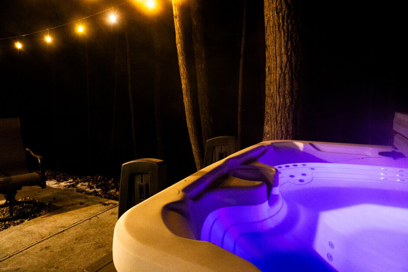 Ein Whirlpool mit einer Hand darauf, umgeben von Bäumen und Lichterketten.