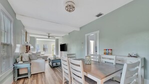 Ein geräumiges Wohnzimmer mit einem Holzessttisch, weißen Stühlen und einem Sofa.
