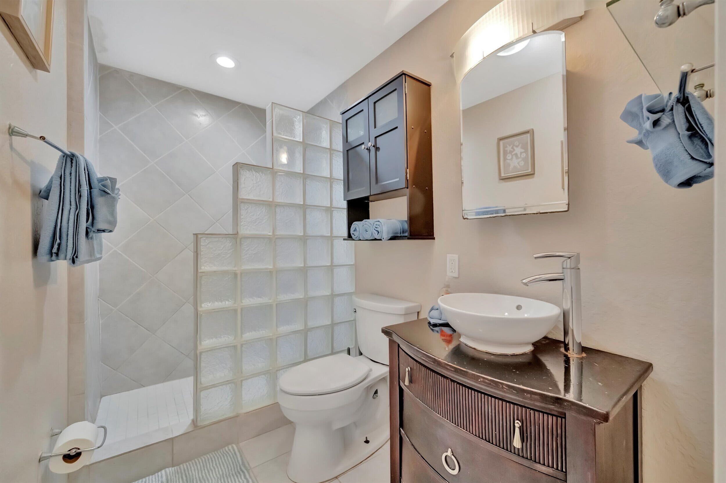 Een badkamer met toilet, wastafel, spiegel en kast.
