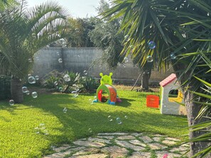 Un espacio al aire libre con césped, una pequeña estructura de juegos y una casita para animales.