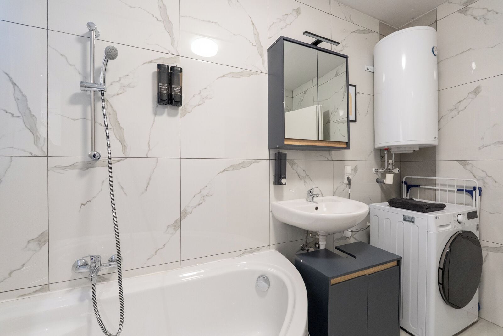 A modern bathroom with a bathtub, a sink, a mirror, and a washing machine.