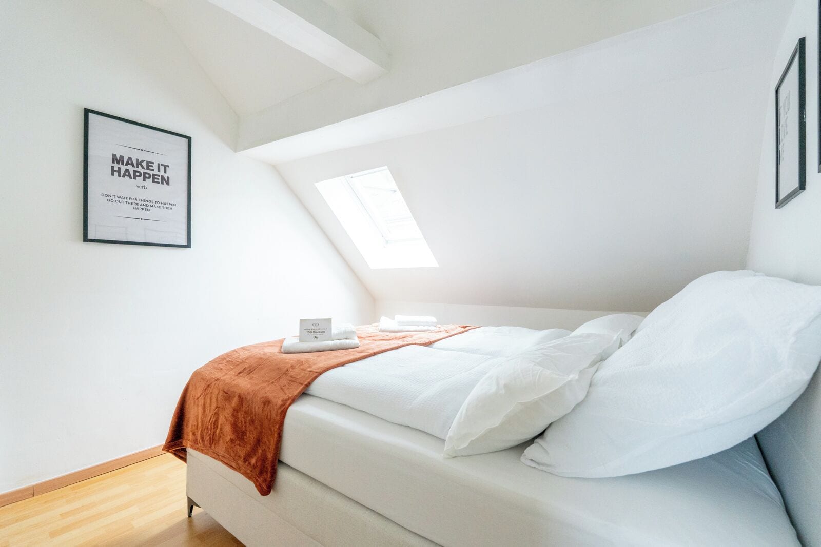 Een slaapkamer met een bed, een raam en een motiverende quote op de muur.