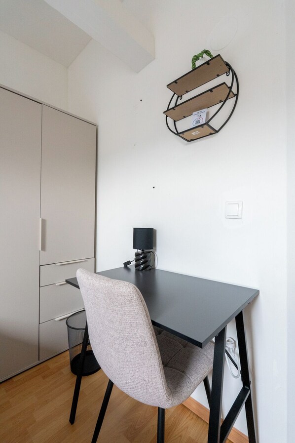 A modern kitchen with a grey table, a grey chair, a black lamp, and a wall-mounted shelf.