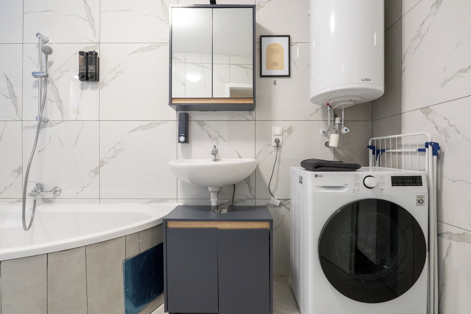 A modern bathroom with a bathtub, sink, mirror, and a washing machine.