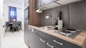 A modern kitchen with a built-in dishwasher, a sink, and a coffee machine. - COY Apartments Kapfenberg (Kapfenberg)