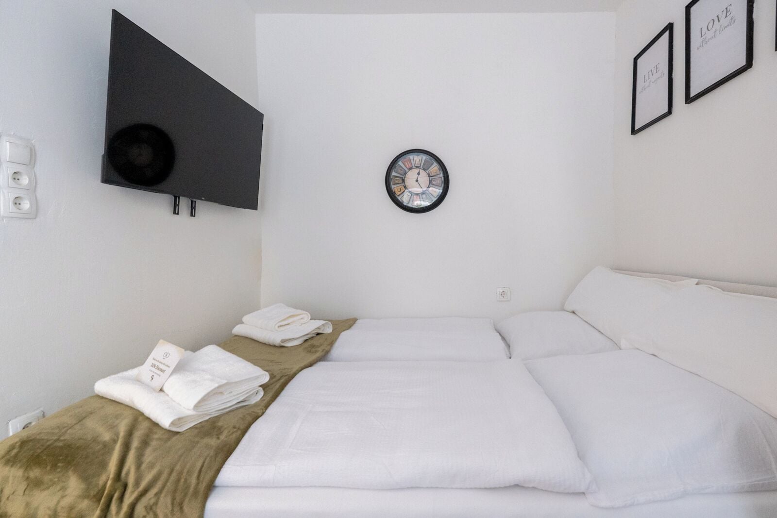 A hotel room with a bed, a TV mounted on the wall, and a framed picture on the wall.
