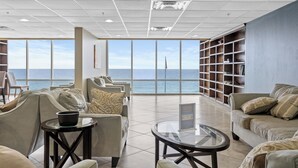 Amplia habitación con un gran ventanal con vistas al mar, amueblada con sofás y una pequeña mesa.