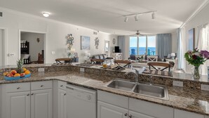 Una cocina amplia con encimeras de granito, armarios blancos y una isla grande con fregadero.
